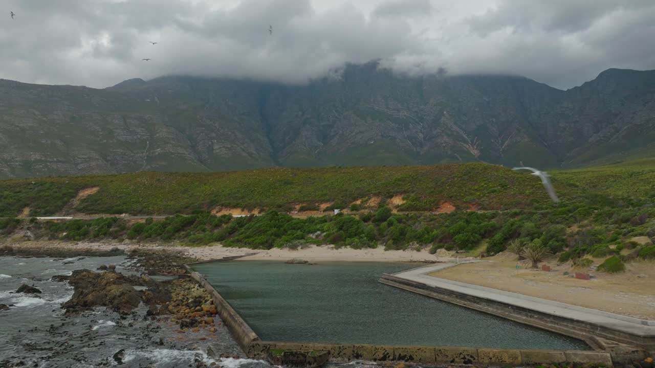 un dron revela gaviotas volando sobre una piscina de marea vacía cerca de ciudad del cabo, sudáfrica