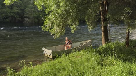 a lady relaxing in a wooden rowboat on a fast flowing mountain river.