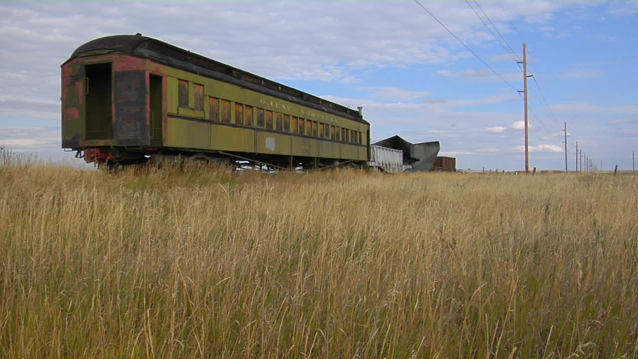 un viejo vagón de tren pullman abandonado se sienta en un campo en un tramo solitario de vía férrea