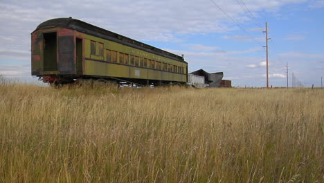 un viejo vagón de tren pullman abandonado se sienta en un campo en un tramo solitario de vía férrea