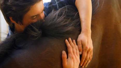 woman embracing horse at stable