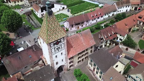 a downward aerial drone footage focusing on the clock tower while revealing the roads and traffic within the village