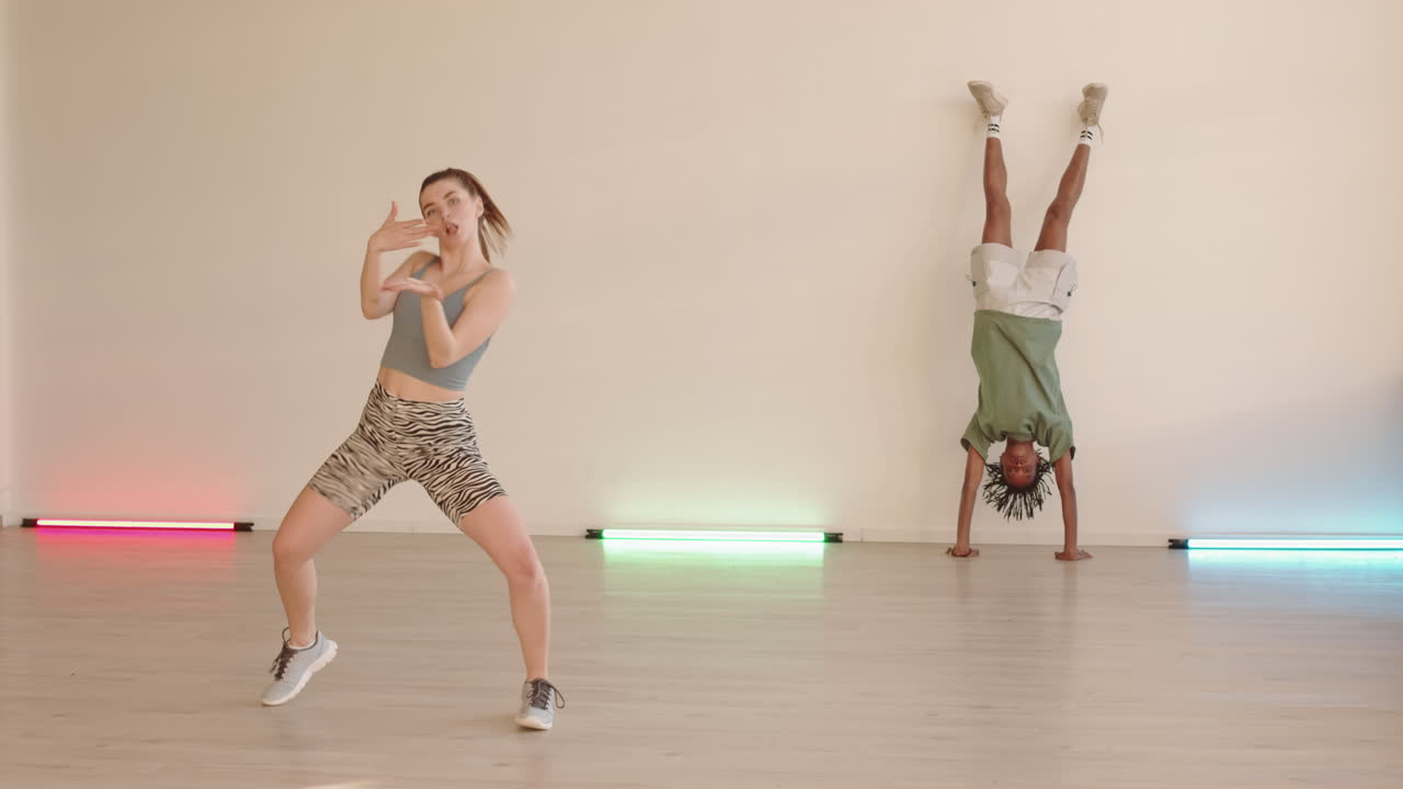 Woman Dancing and Man Standing on Hands