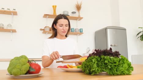 attractive middleaged brunette woman preparing food in modern white kitchen attractive middleaged brunette woman preparing food in modern white kitchen vegan woman prepares vegetables and greens