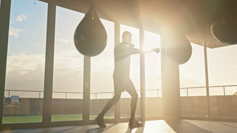 Boxer,-fitness-and-punching-bag-by-man-at-sunrise