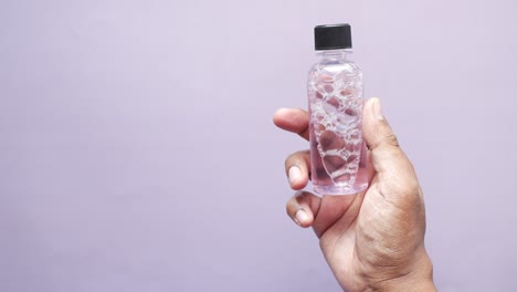 person holding a small bottle of pink liquid