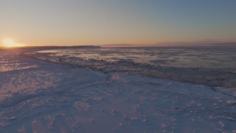 Colorida-Puesta-De-Sol-Sobre-Un-Lago-Congelado-Y-Una-Costa-Nevada-En-Alaska