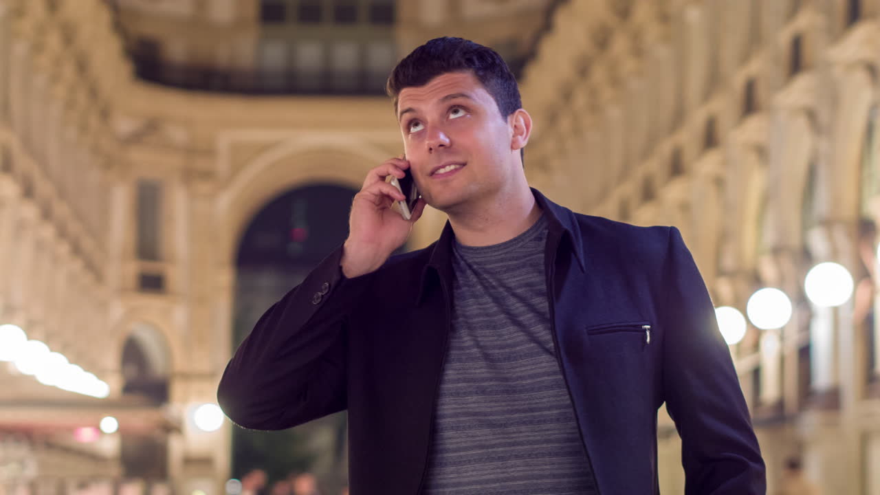 밤에 도시에서 전화로 대화하는 남자