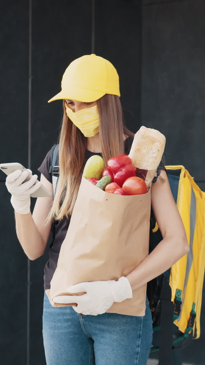Delivery person wearing a mask holding a grocery bag with fresh produce
