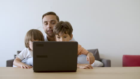 Padre-Mostrando-Algo-En-La-Computadora-Portátil-A-Sus-Hijos-Pequeños