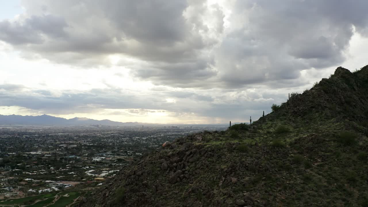 Drone shot revealing Scottsdale, Arizona from behind Camelback Mountain on a cloudy day