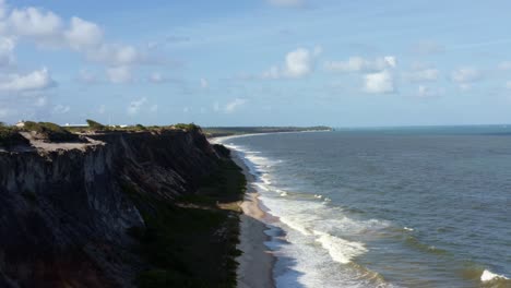 toma de drones aéreos a la derecha de enormes y hermosos acantilados blancos en la costa en el estado tropical de paraiba, brasil cerca de la capital de la playa de brasil en un cálido día soleado de verano con pequeñas olas
