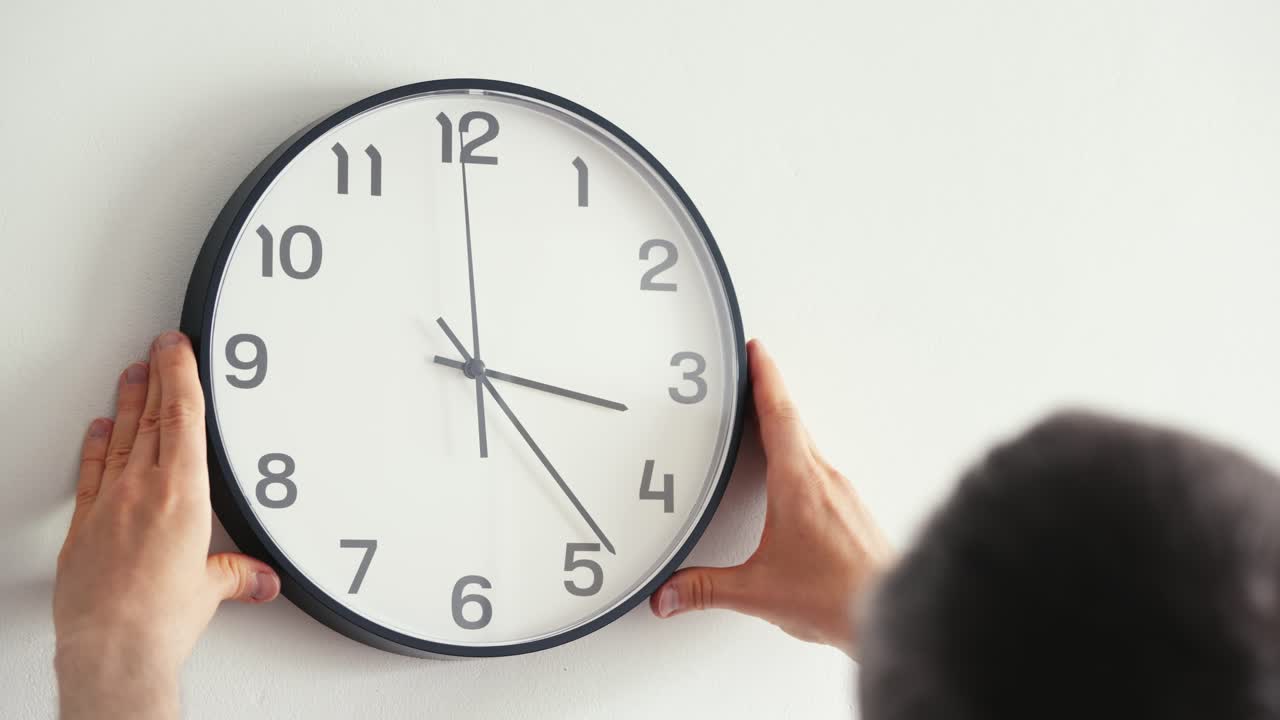 Hombre colocando un reloj en la pared