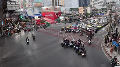 motorcycles and cars navigating a crowded crossroad.