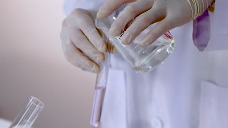scientist pouring liquid from test tube to beaker in lab