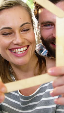 cute couple smiling behind a wood shape