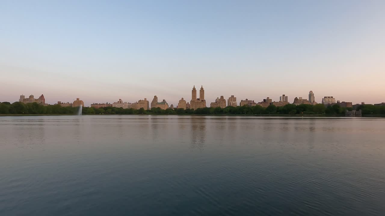 A mesmerizing dawn timelapse captures the urban beauty of Manhattan's Upper West Side as viewed across Central Park's reservoir lake