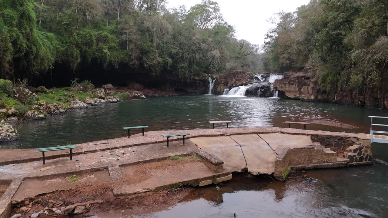 Aerial view of the Gruta India Natural Park, located in Misiones, Argentina, featuring the serene waterway and footbridge surrounded by lush greenery