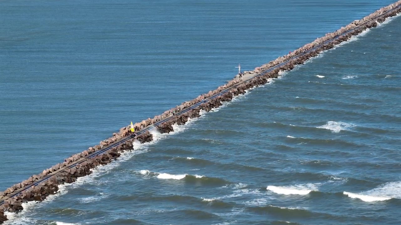 Vista estática em telefoto do quebra-mar rochoso e do espantalho de vela nos Molhes da Barra em Rio Grande, Brasil.