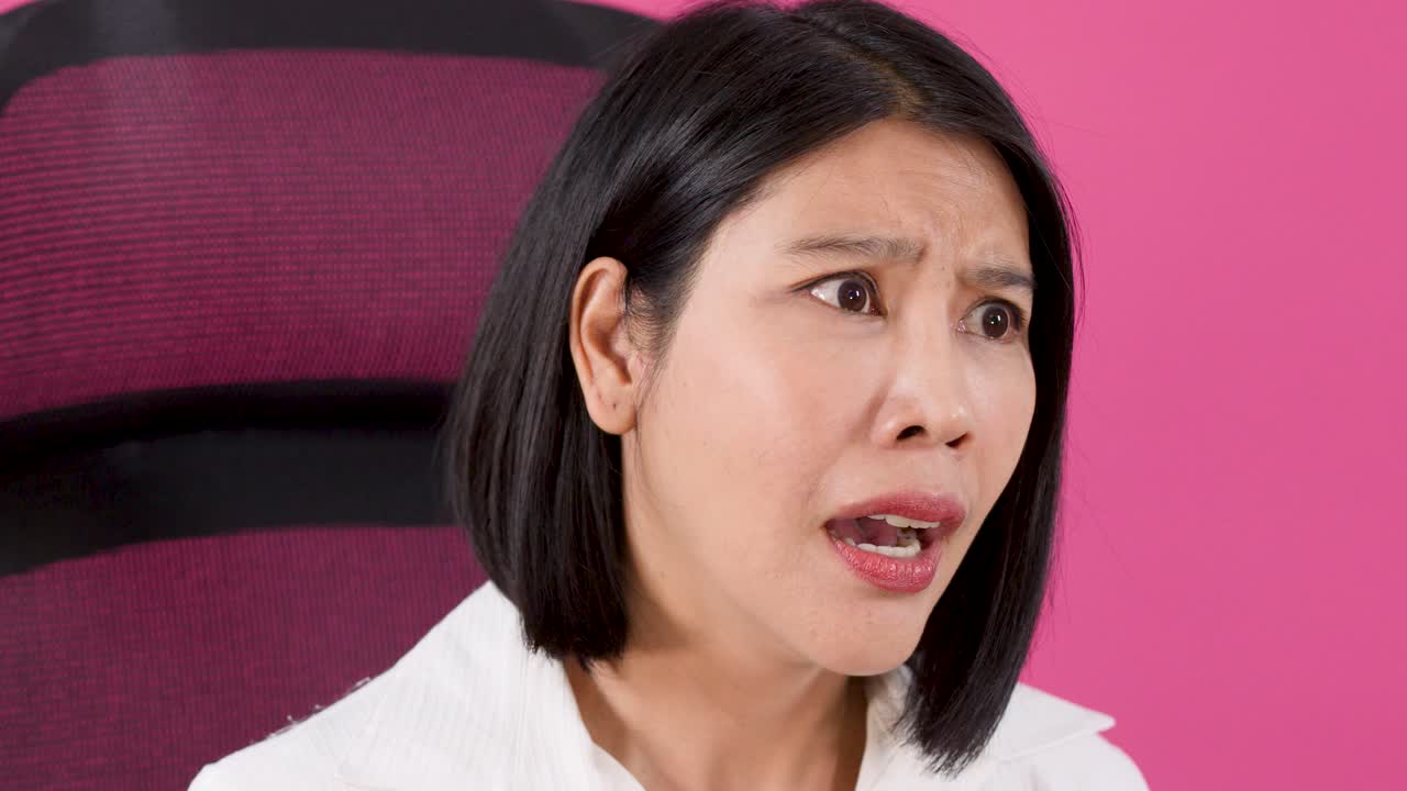 사무실 의자에 앉아 충격과 불신에 반응하며 걱정하는 아시아 여성의 클로즈업