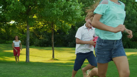 Children-with-parents-running-in-summer-park.-Joyful-family-playing-in-meadow