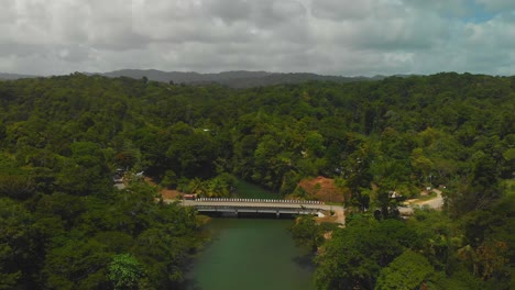 aerial footage of a bridge over a river with a rainforest in the background at this epic northcoast location in trinidad and tobago