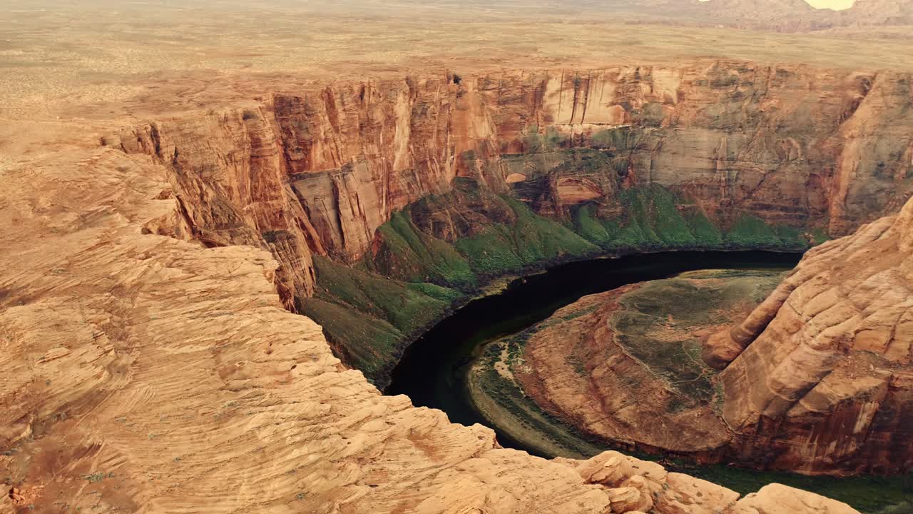 Smooth sideward flight descends toward canyon curve, Arizona desert, golden hour