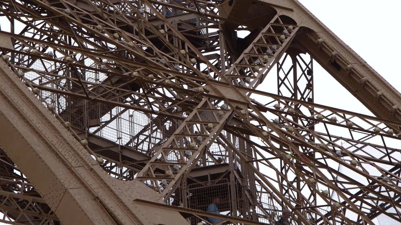 Close-up View of Eiffel Tower's Intricate Iron Structure with Visitors