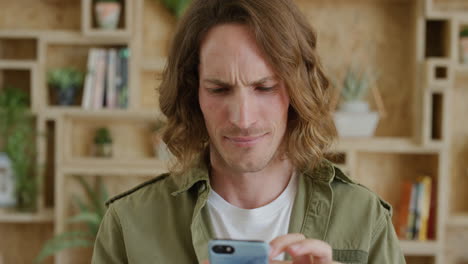 retrato en primer plano de un joven que usa un teléfono inteligente, envía mensajes de texto, navega, disfruta leyendo mensajes en las redes sociales, sonríe en cámara lenta