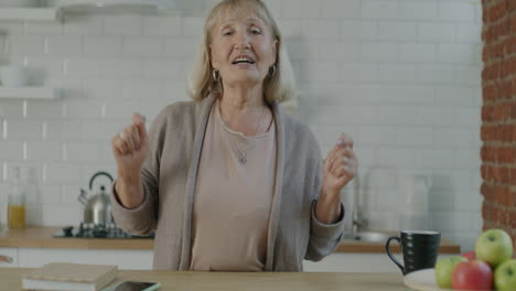 senior woman engaging in a video call and stretching in a kitchen