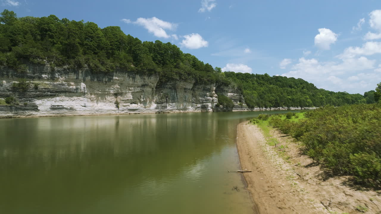 спокойная береговая линия бобрового озера с пышной зеленью и спокойной водной поверхностью под солнечным небом