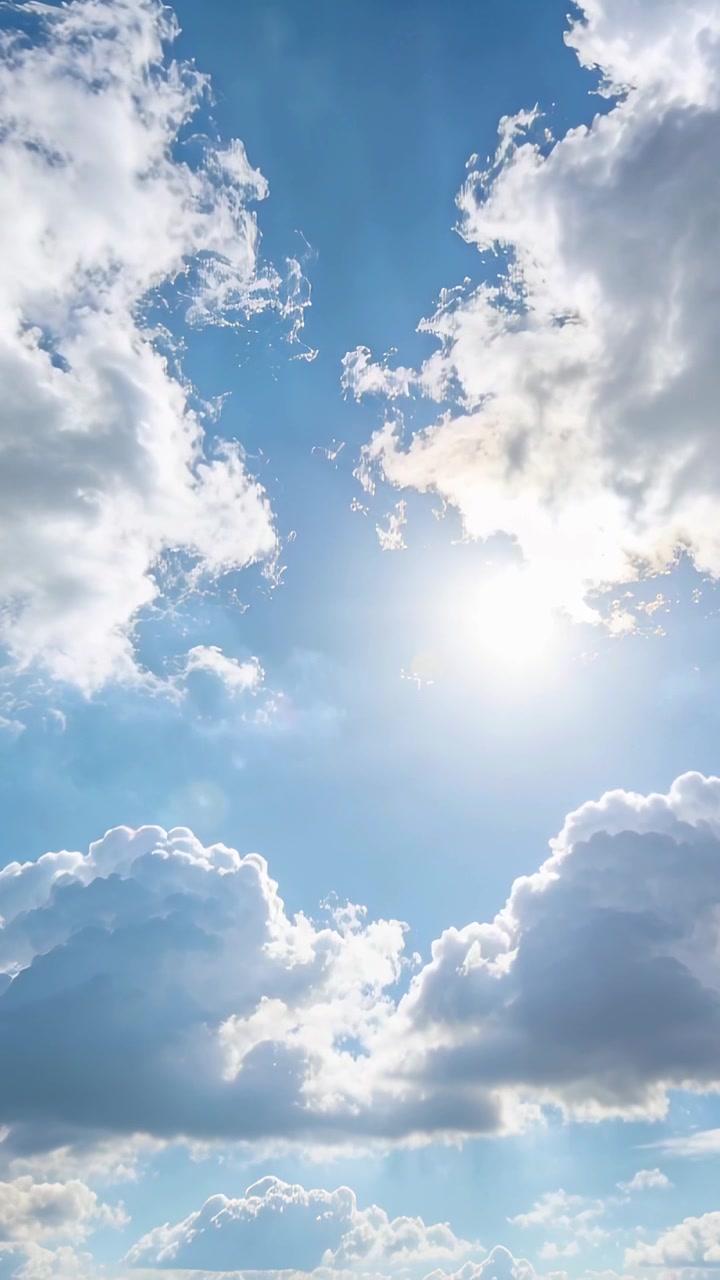 Video vertikal: Awan kumulus yang bergeser melayang di atas, menampakkan matahari melalui gumpalan awan tipis.