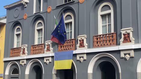 european and italian flags are waving over ukrainian flag on the balcony