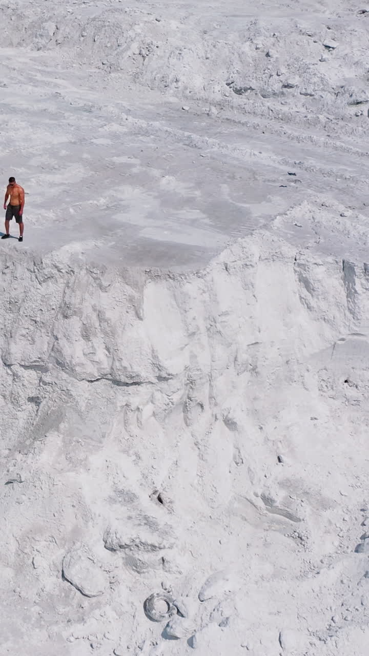 White canyon and a sportsman. View from above on strong athlete standing on the top of the hill. Aerial view. Vertical video