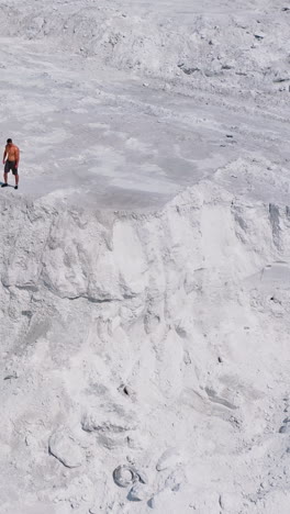 white canyon and a sportsman. view from above on strong athlete standing on the top of the hill. aerial view. vertical video