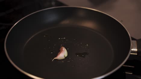 el chef frota la superficie caliente de la sartén con un guante de ajo.