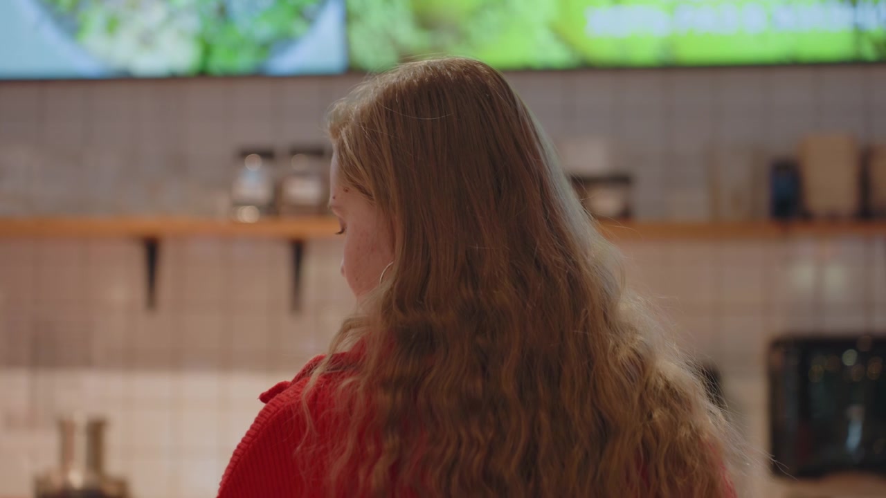 Young Woman with Long Hair Looking at Menu in Cafe