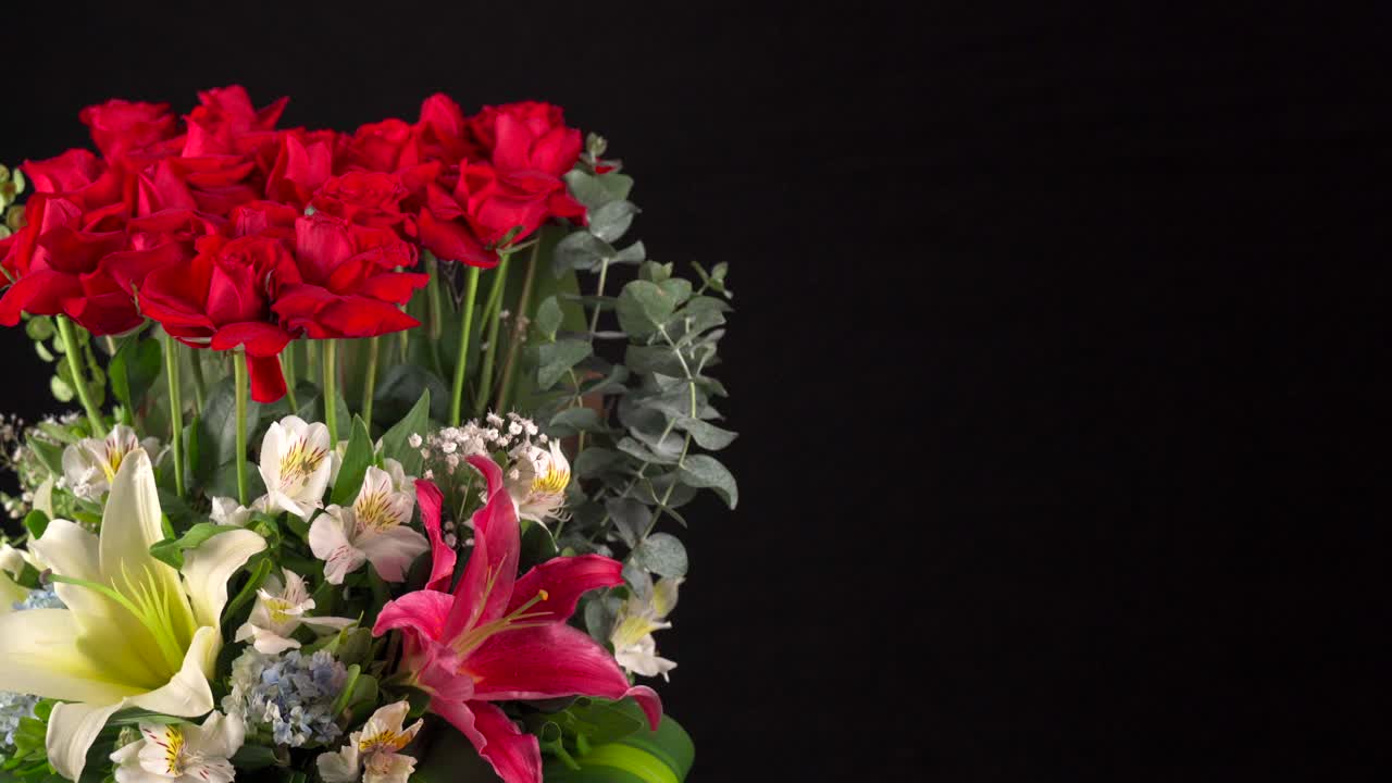 Bouquet di fiori ripreso con slider su sfondo nero: rose, orchidee, gigli.