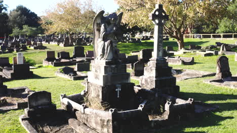 drone flying towards the statue of an angel in a graveyard cemetery on a sunny day