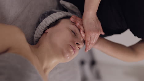 chiropractor making woman relaxing spa face massage breathing head lifting exercises in beauty salon