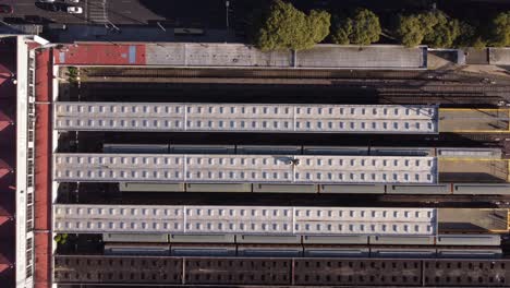 Aerial-top-down-shot-of-public-train-approaching-train-station-of-Federico-Lacroze-Station-in-Buenos-Aires