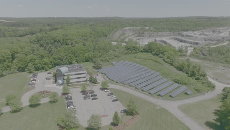 Drone-Push-out-and-Push-in,-beautiful-Massachusetts-office-with-solar-panels-quarry-in-background