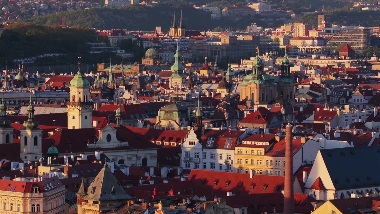 Vista aerea con drone del centro storico di Praga con numerose guglie barocche a cupola verde e tetti di tegole rosse che si estendono in lontananza sotto la calda luce della sera, Praga, Repubblica Ceca.