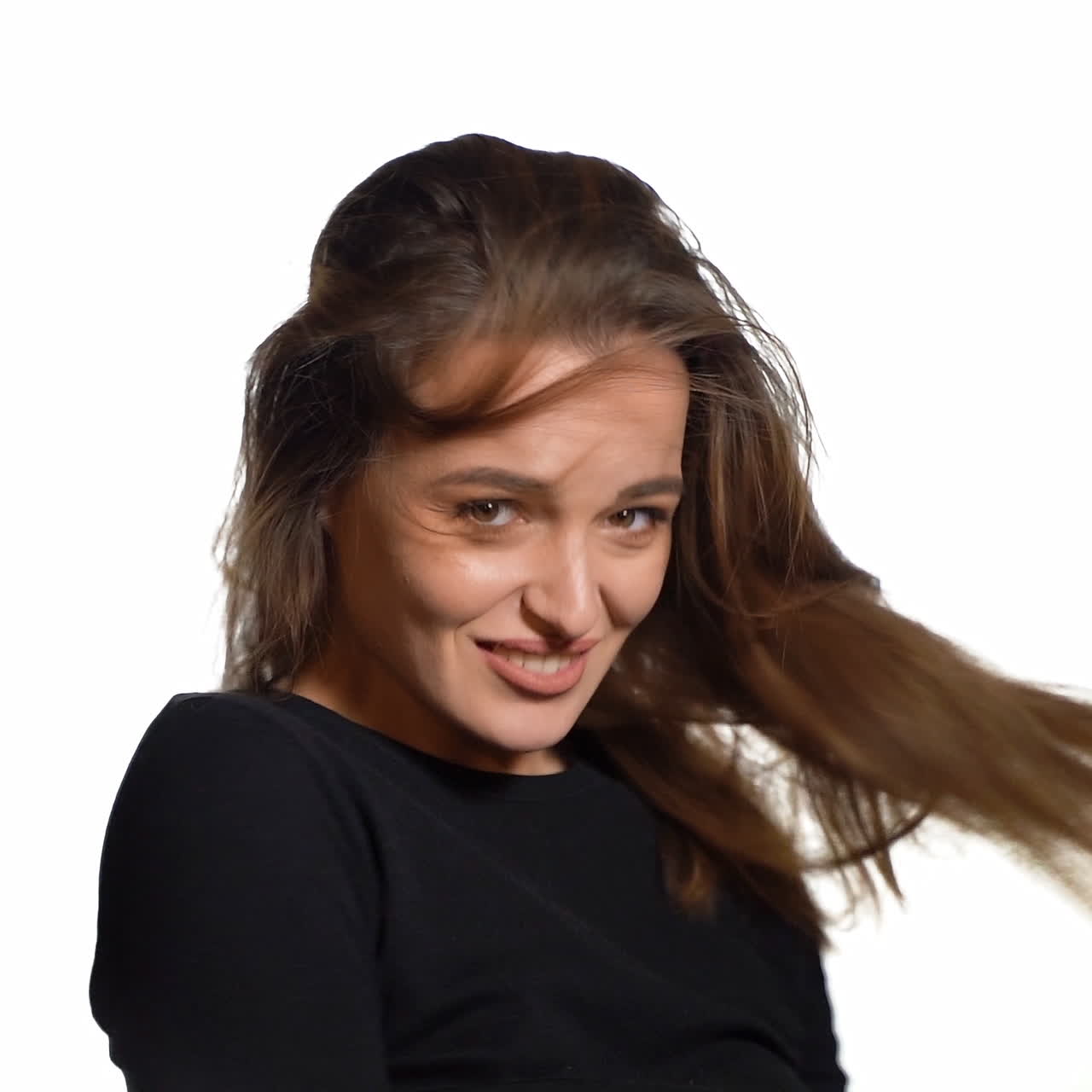 A passionate woman with brown hair tilts her hair back on a white background in the studio. Close-up.