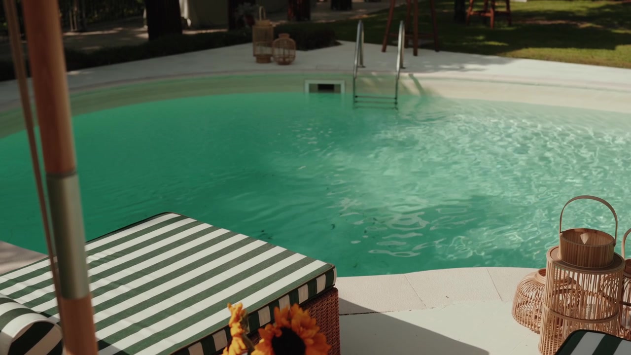 Green Striped Sunbed and Rattan Lantern beside Clear Turquoise Pool Water at Summer Villa