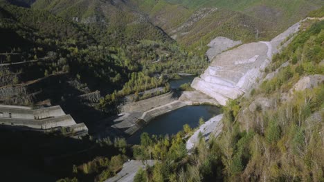 Aerial-side-pan-of-large-dam-in-the-mountains-in-spring