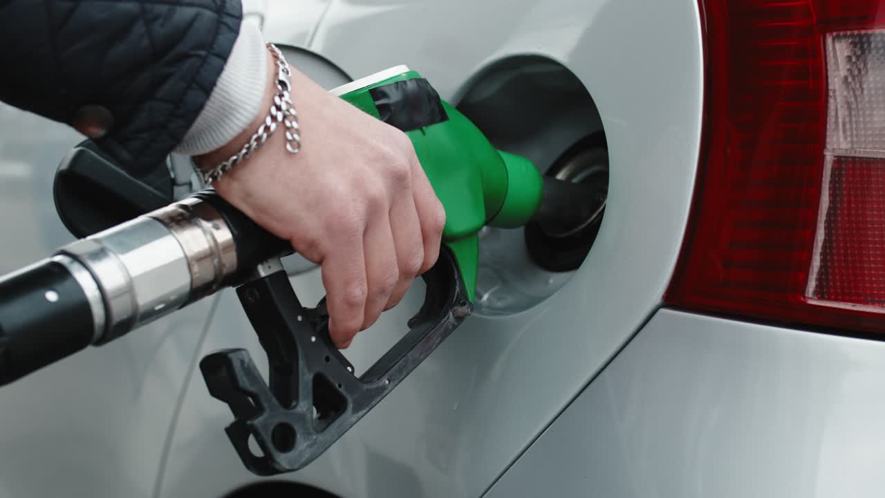 주유소 사람 의 손 이 차 에 가솔린 을 넣고 있다