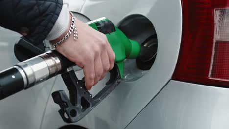 hand of a gas station man is putting gasoline into a car