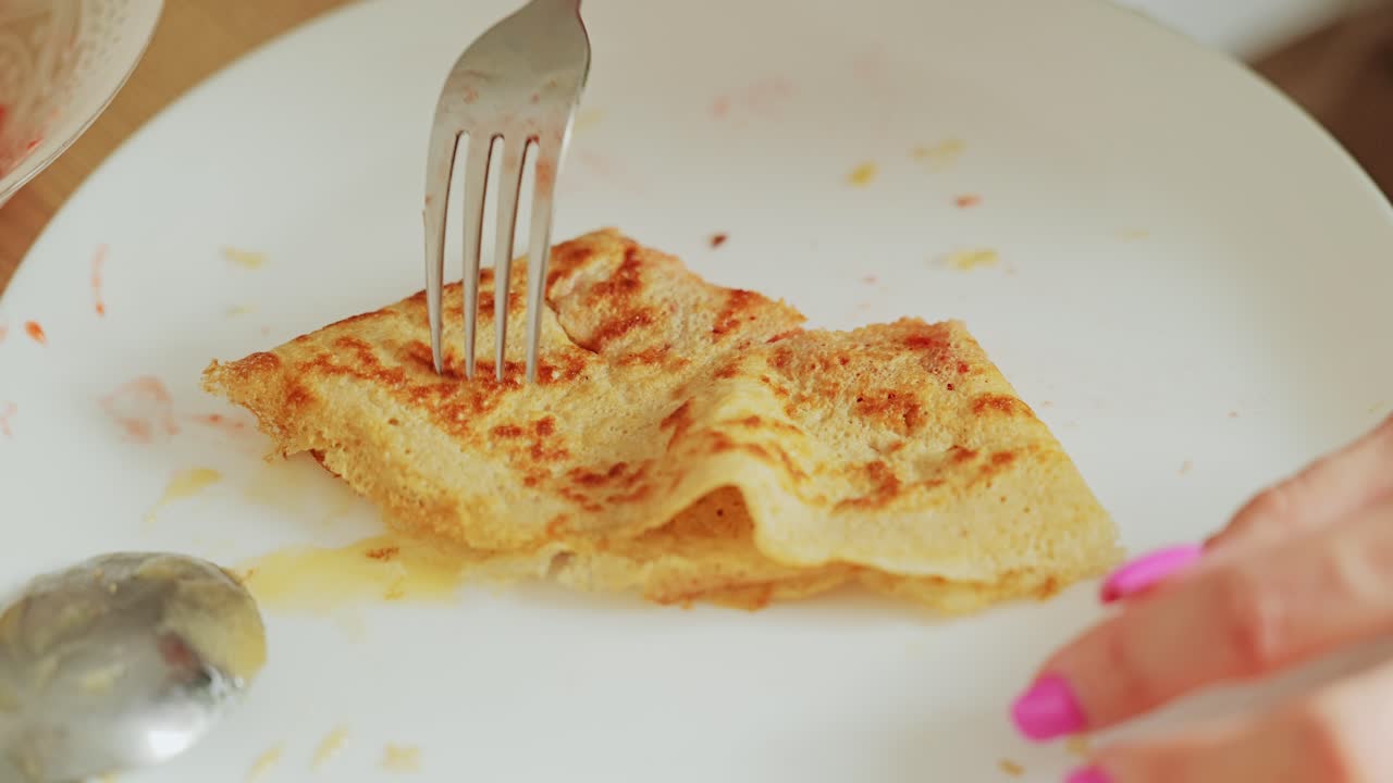 Golden crepes with fruit filling eaten by young woman at peaceful morning meal