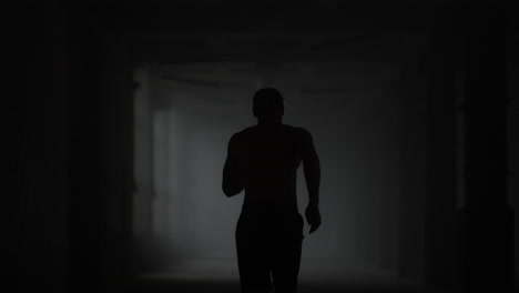 Fitness-man-running-in-dark-corridor.-Male-jogger-training-in-loft-building